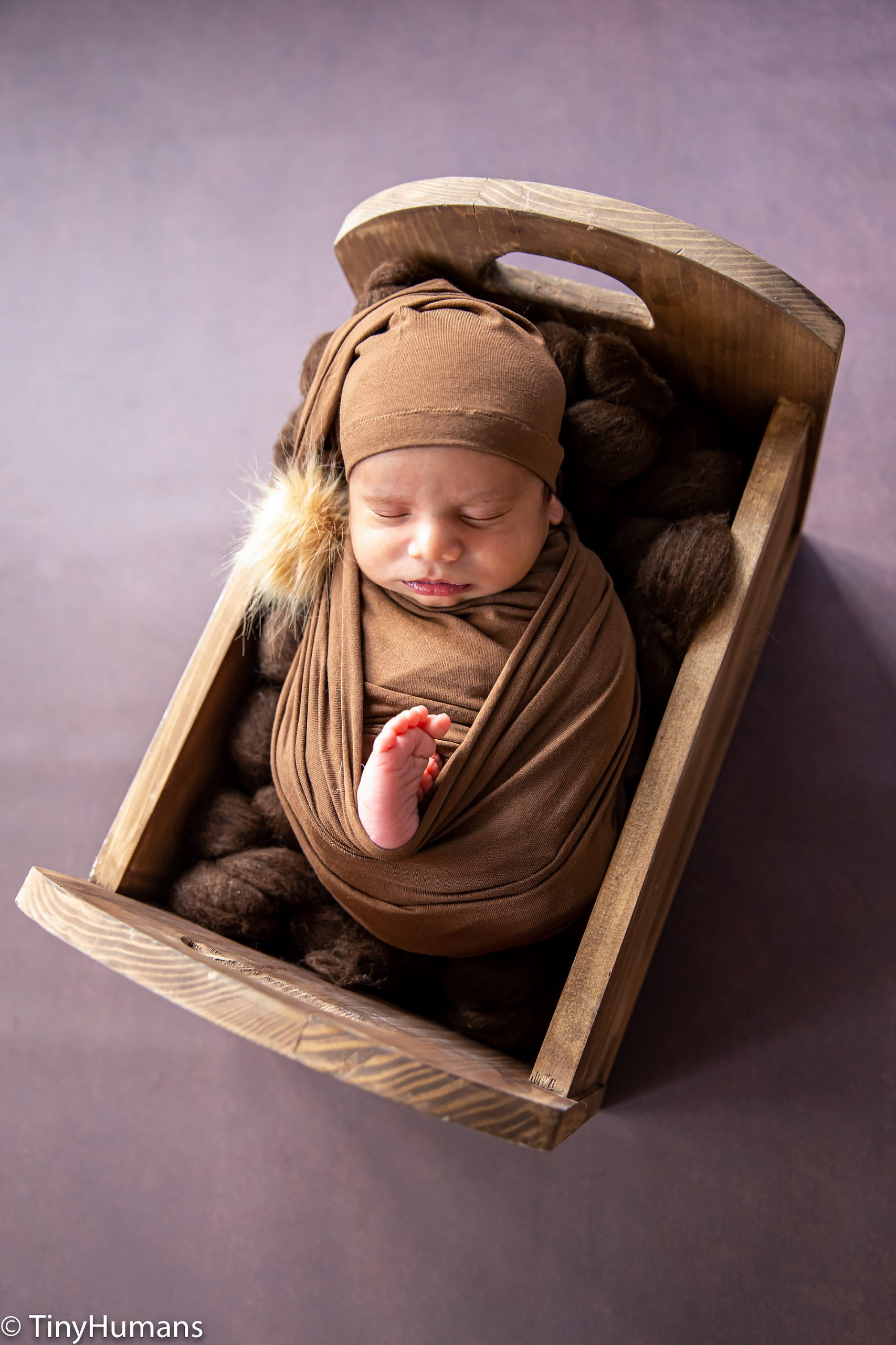 Newborn baby on brown wrap and backdrop