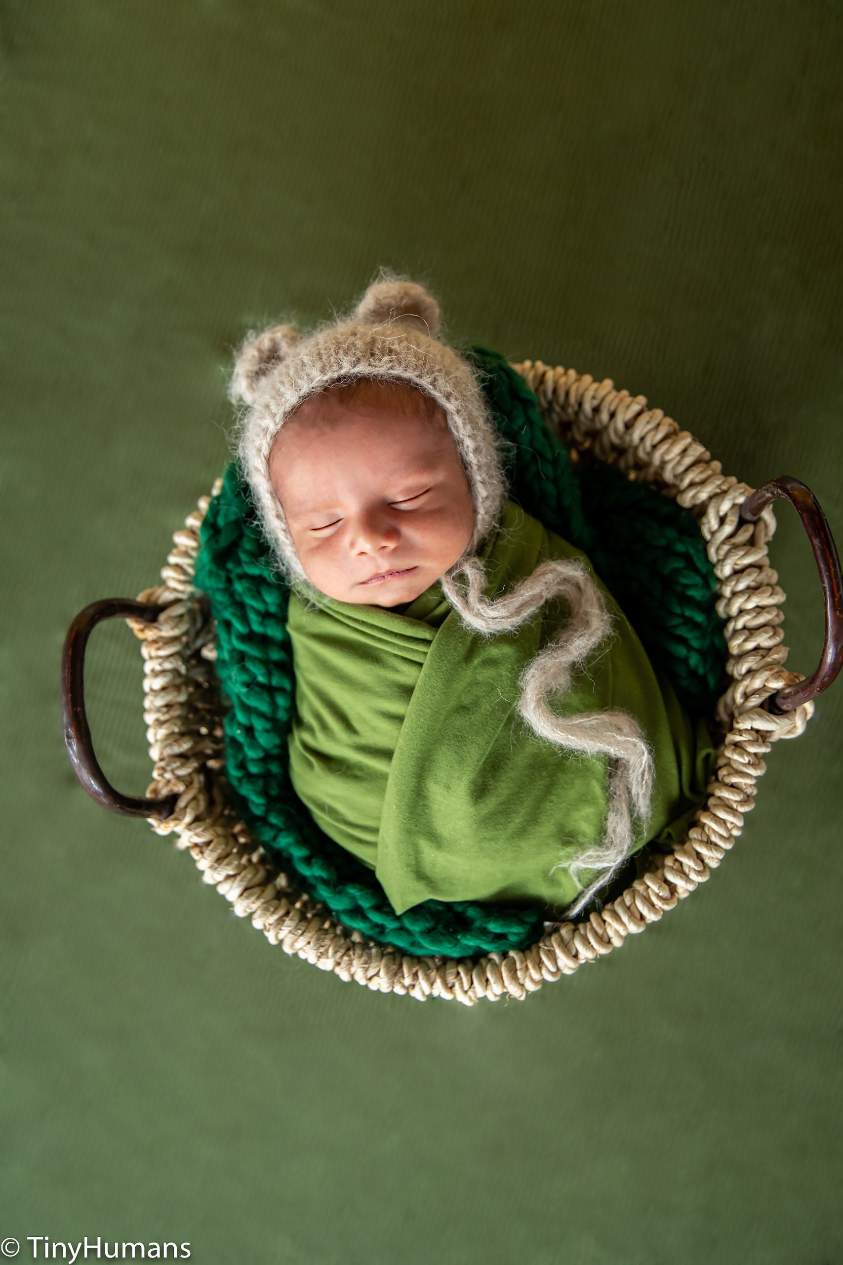Newborn baby on green wrap and backdrop